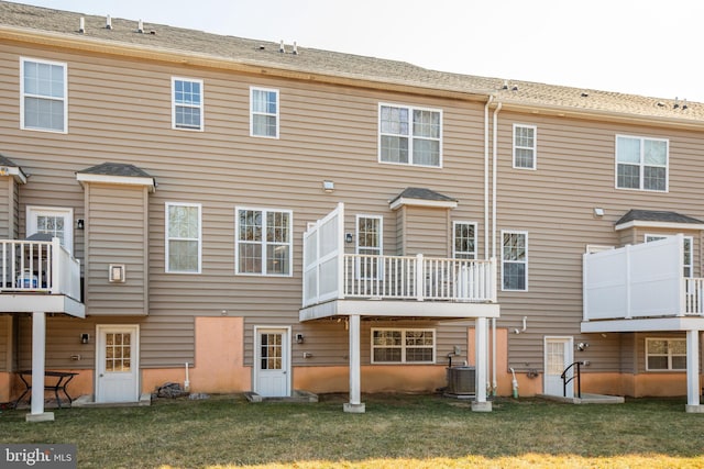 back of property with central air condition unit and a lawn