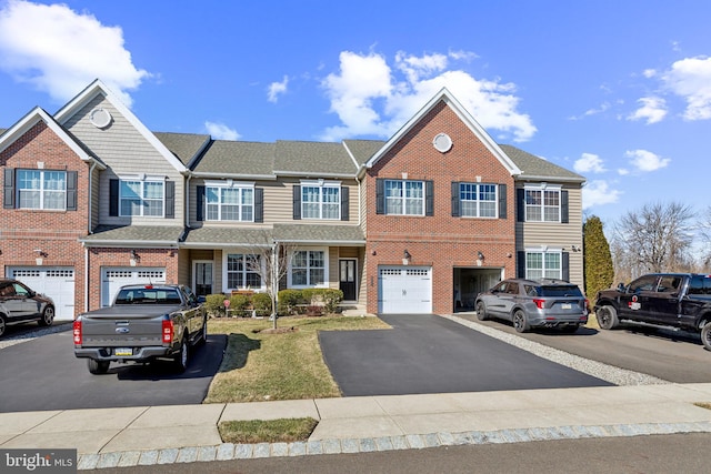 townhome / multi-family property featuring brick siding, driveway, a garage, and roof with shingles