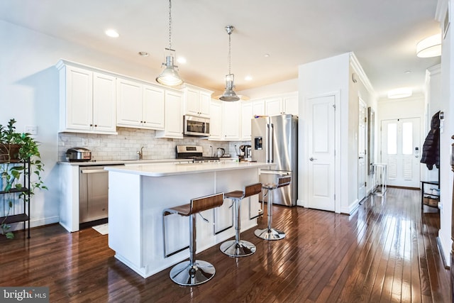 kitchen featuring tasteful backsplash, appliances with stainless steel finishes, dark wood-style floors, and hanging light fixtures