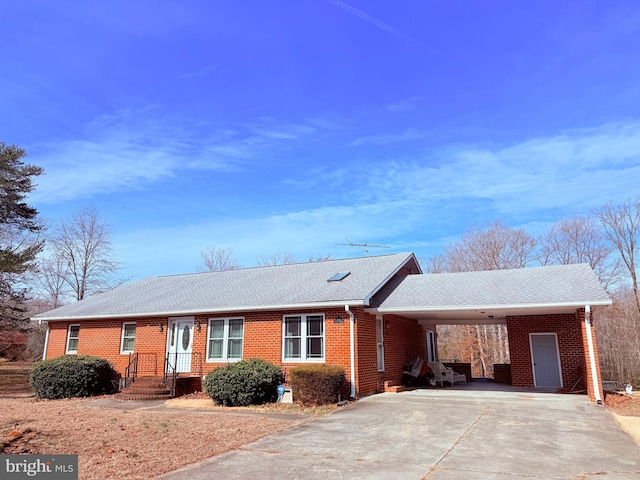 ranch-style home featuring brick siding, an attached carport, and driveway