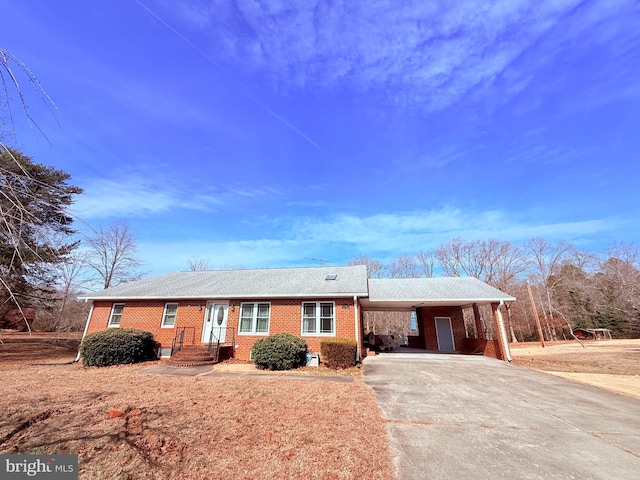 ranch-style house with brick siding, concrete driveway, and a carport