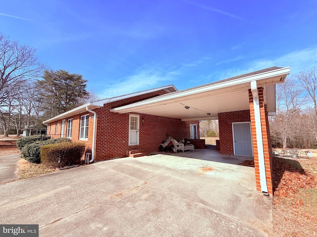 view of property exterior featuring an attached carport, brick siding, and concrete driveway