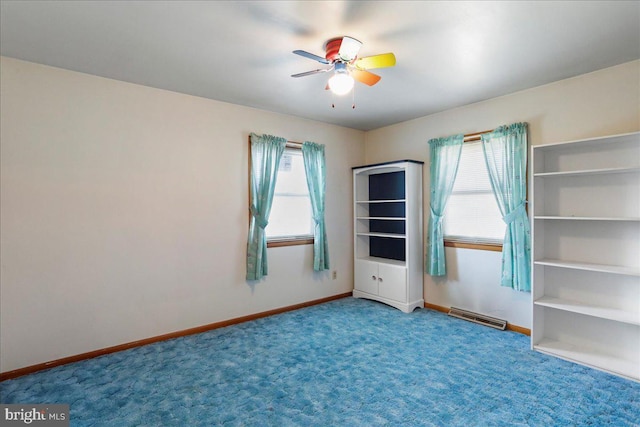 carpeted empty room featuring visible vents, baseboards, and ceiling fan