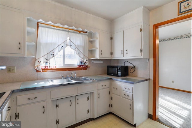 kitchen featuring light floors, open shelves, a sink, black microwave, and white cabinetry