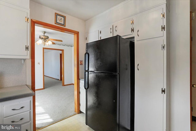 kitchen with light carpet, freestanding refrigerator, white cabinets, light floors, and ceiling fan