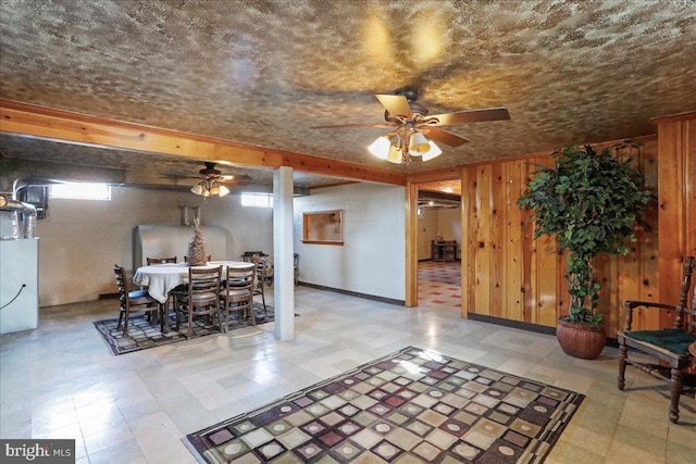 dining space with tile patterned floors, wooden walls, baseboards, and a ceiling fan