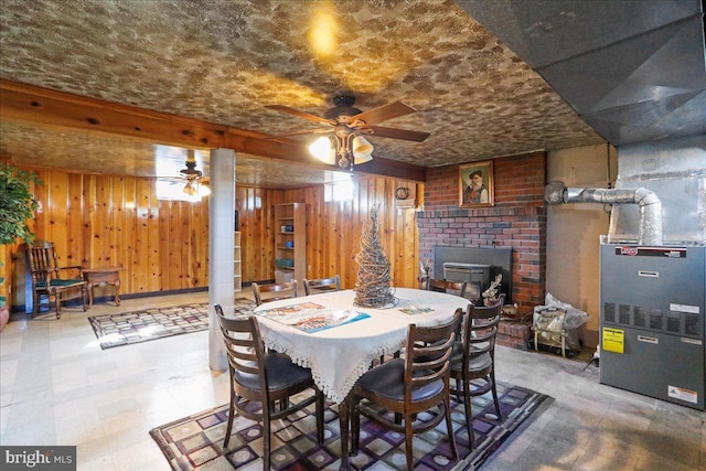 dining area featuring tile patterned floors, heating unit, wood walls, and ceiling fan