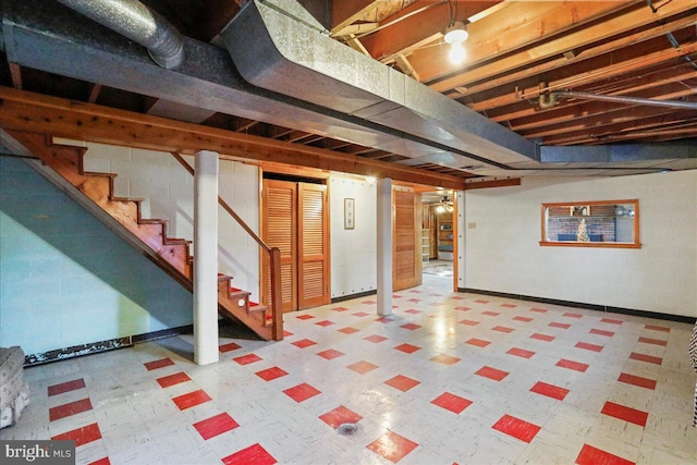 unfinished basement featuring tile patterned floors, concrete block wall, and stairs