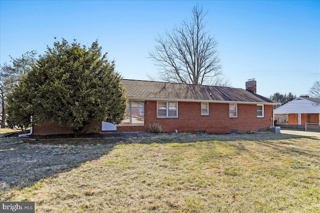 view of side of home featuring a yard, central AC unit, brick siding, and a chimney