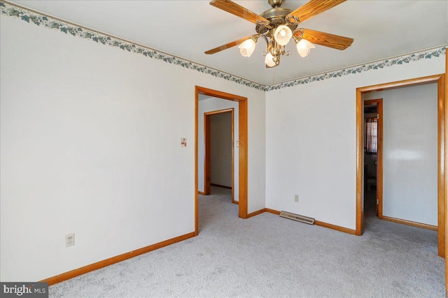 carpeted empty room featuring visible vents, ceiling fan, and baseboards