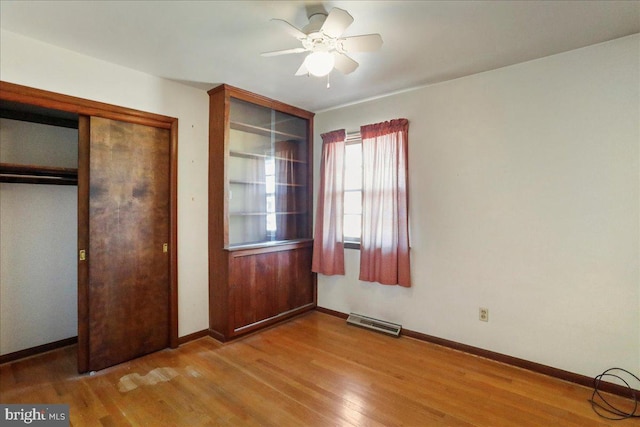 unfurnished bedroom featuring visible vents, baseboards, wood finished floors, a closet, and a ceiling fan