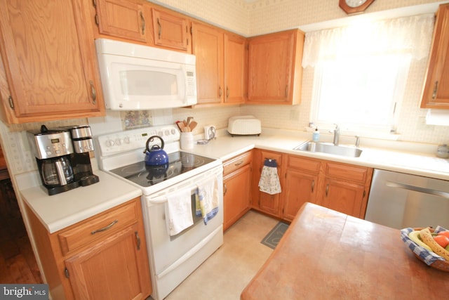 kitchen featuring a sink, white appliances, and light countertops