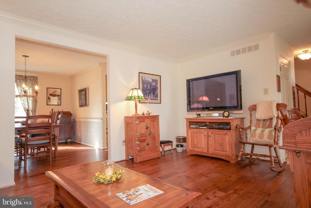 living room featuring visible vents, wood finished floors, crown molding, and a chandelier