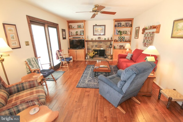 living area with a fireplace, wood-type flooring, and ceiling fan