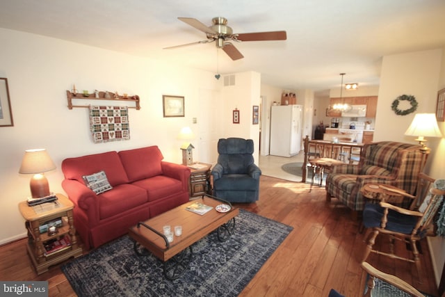 living area featuring hardwood / wood-style flooring, ceiling fan with notable chandelier, and visible vents