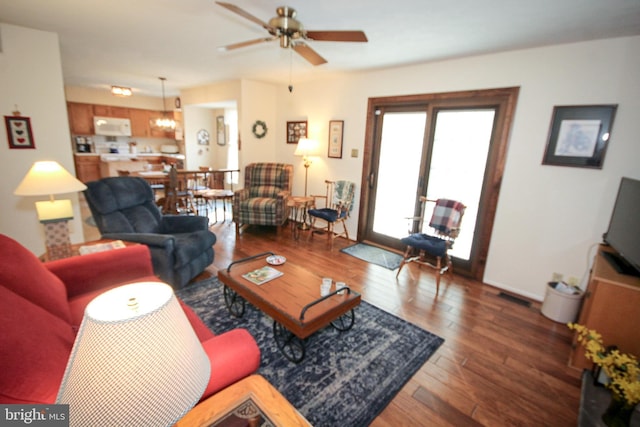 living area with wood finished floors, visible vents, and ceiling fan