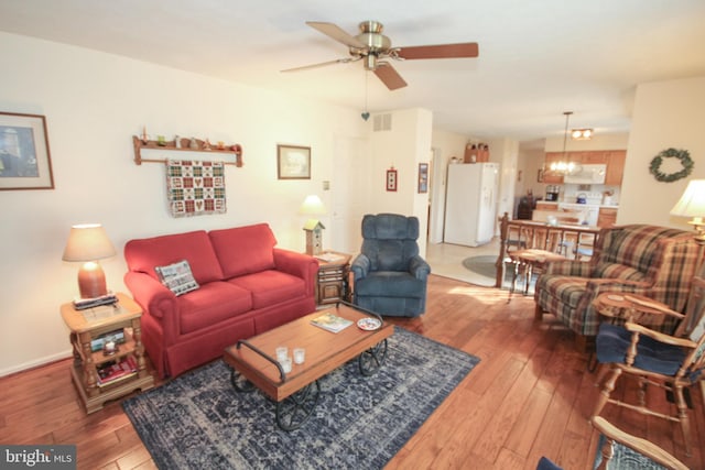 living area with hardwood / wood-style floors, baseboards, visible vents, and ceiling fan