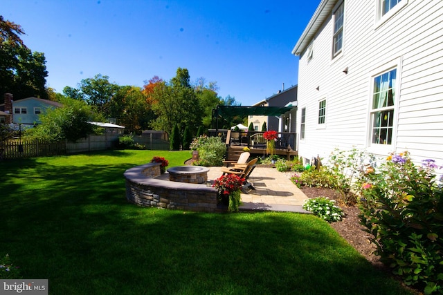 view of yard with a deck, a patio area, a fire pit, and a fenced backyard