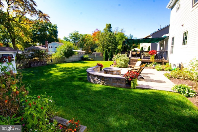 view of yard with a wooden deck, a fire pit, a fenced backyard, and a patio area