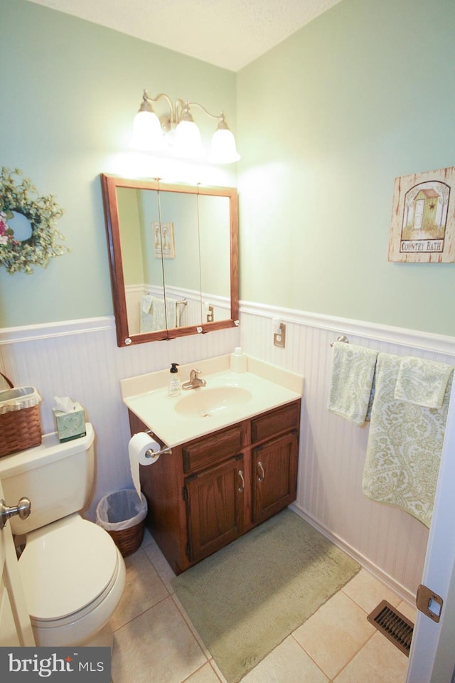 half bathroom featuring a wainscoted wall, visible vents, and tile patterned flooring