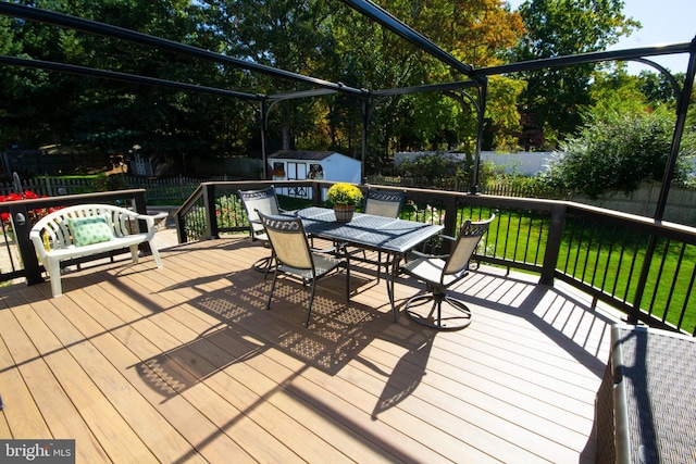 wooden terrace with an outbuilding, a shed, outdoor dining area, a fenced backyard, and a yard