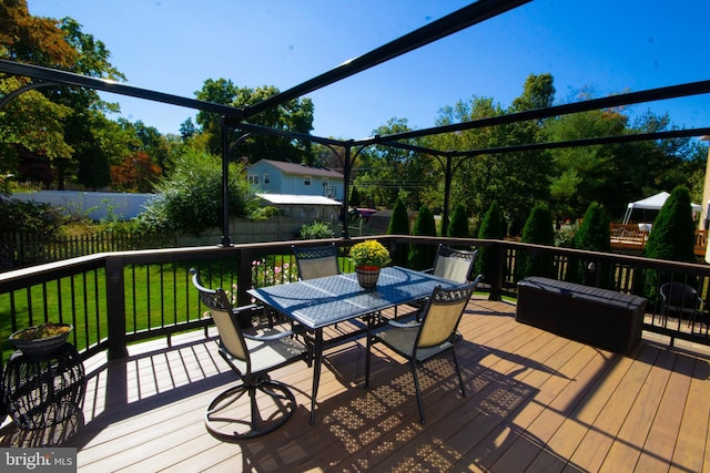 wooden deck featuring outdoor dining area, fence, and a lawn