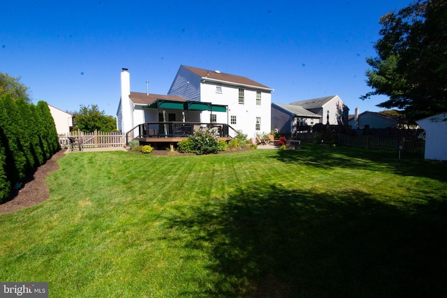 back of house with a deck, a fenced backyard, a lawn, and a chimney