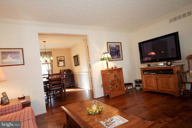 living area with visible vents, a notable chandelier, ornamental molding, and dark wood-style flooring