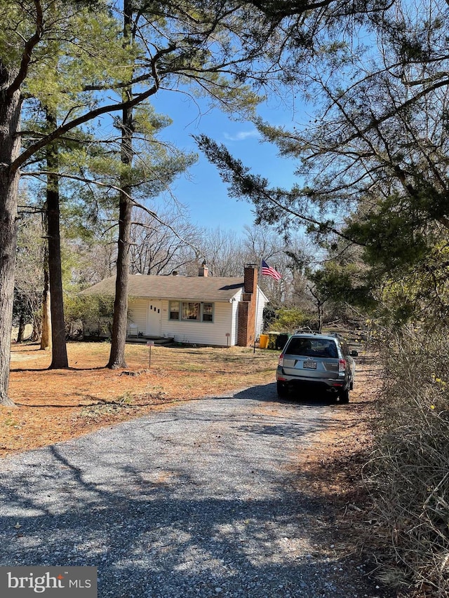 view of front of home with a chimney and gravel driveway