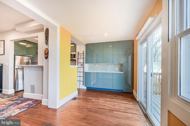 interior space featuring visible vents, baseboards, decorative backsplash, appliances with stainless steel finishes, and wood finished floors