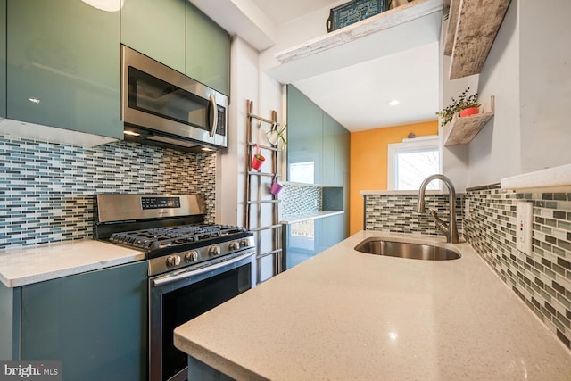 kitchen featuring a sink, tasteful backsplash, appliances with stainless steel finishes, and green cabinets