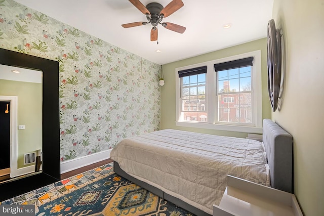 bedroom featuring wallpapered walls, wood finished floors, and baseboards