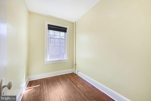 spare room featuring baseboards and dark wood-style flooring