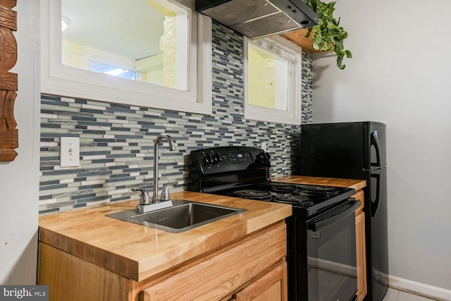 kitchen with under cabinet range hood, butcher block countertops, electric range, and a sink