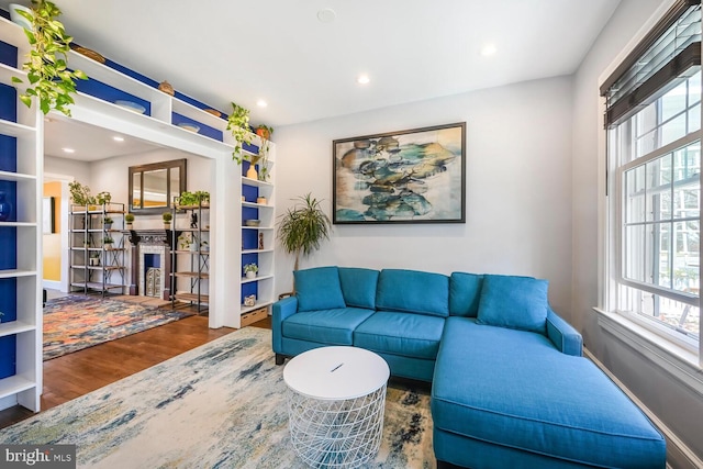 living area with a fireplace, recessed lighting, wood finished floors, and a healthy amount of sunlight