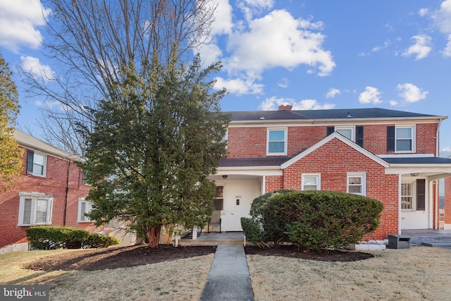 view of front of house with brick siding and a chimney