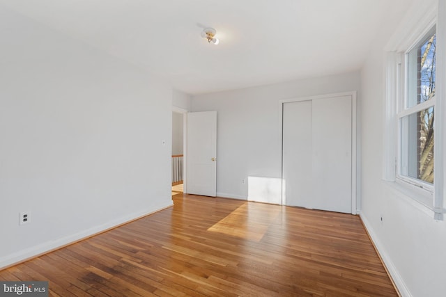 unfurnished bedroom with a closet, baseboards, and hardwood / wood-style flooring