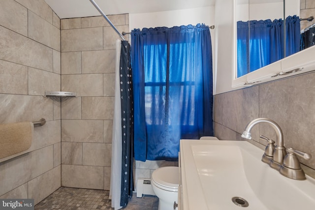 bathroom featuring a tile shower, baseboard heating, tile walls, and a sink