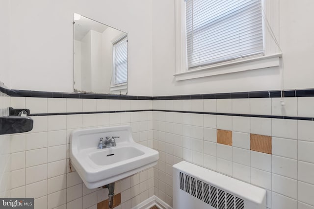 bathroom with wainscoting, radiator, tile walls, and a sink