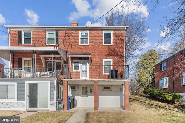 rear view of property featuring central air condition unit, brick siding, a chimney, and a lawn