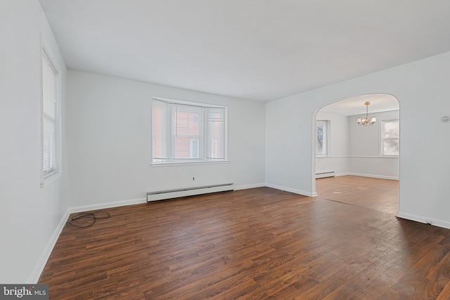 empty room featuring arched walkways, a baseboard heating unit, baseboards, and wood finished floors