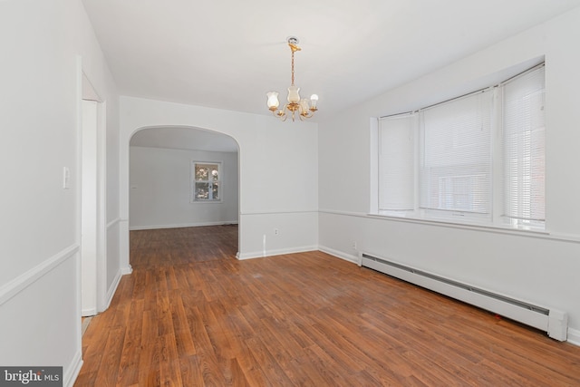 spare room with wood finished floors, arched walkways, baseboards, baseboard heating, and a chandelier