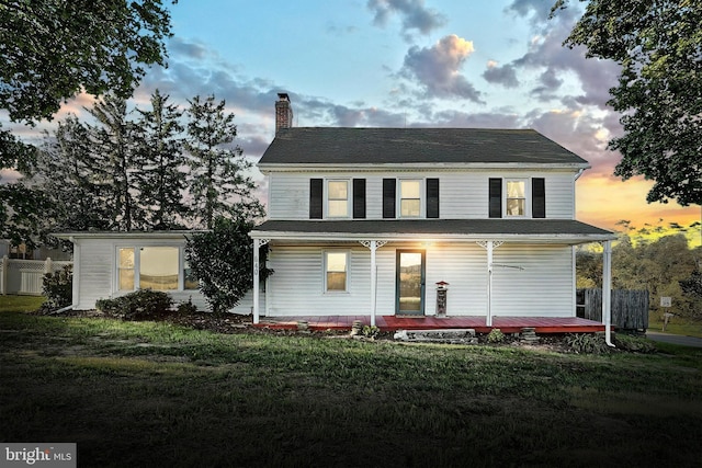 view of front facade with a chimney, a front lawn, and fence