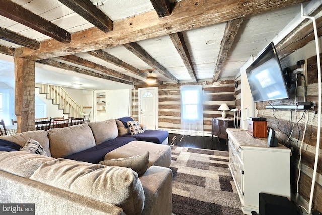 living room featuring dark wood finished floors, beamed ceiling, and stairway