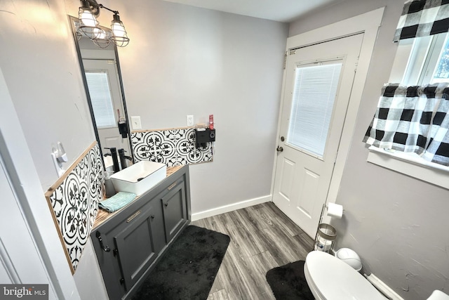 bathroom with baseboards, toilet, wood finished floors, and vanity