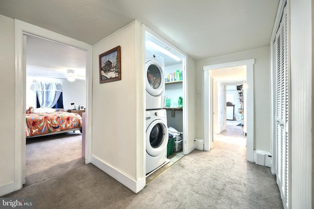 washroom with laundry area, stacked washer and dryer, carpet flooring, and baseboards