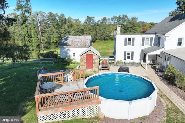 outdoor pool with an outbuilding, a lawn, fence, a storage shed, and a wooden deck