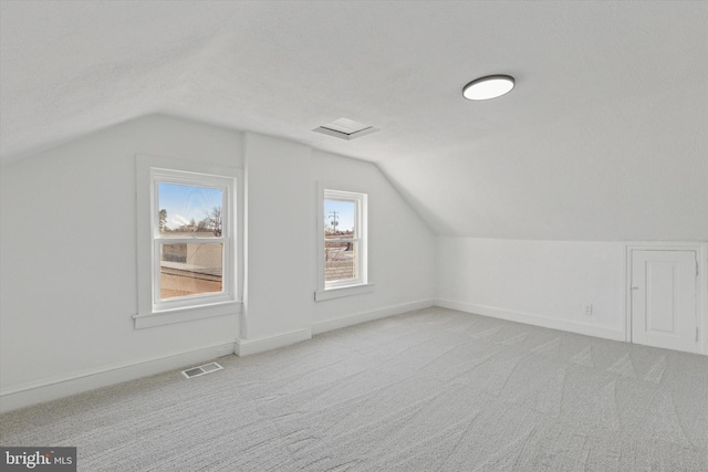 additional living space featuring visible vents, carpet floors, baseboards, and vaulted ceiling