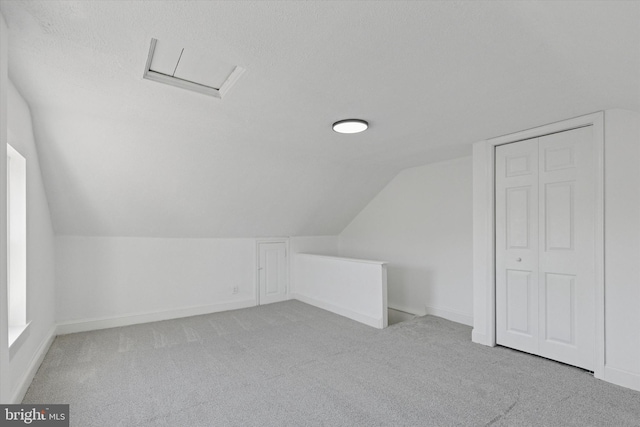 bonus room with attic access, carpet, baseboards, and vaulted ceiling