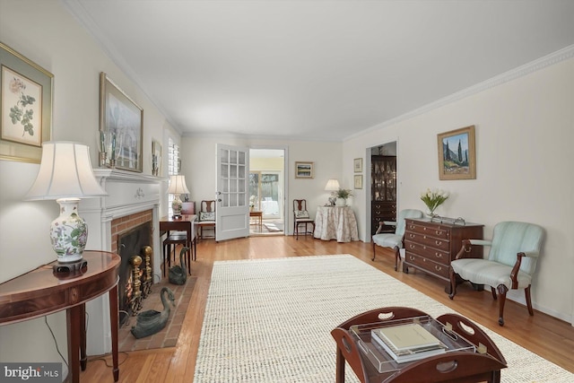 living room featuring a brick fireplace, wood finished floors, and ornamental molding